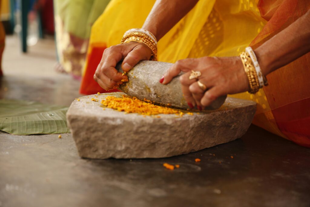 Close-up of hands grinding turmeric for an Indian wedding haldi ceremony in Kolkata, India.